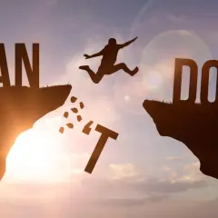 Sylwetka skaczącego człowieka nad przepaścią, litery "I CAN DO IT" na tle zachodzącego słońca.